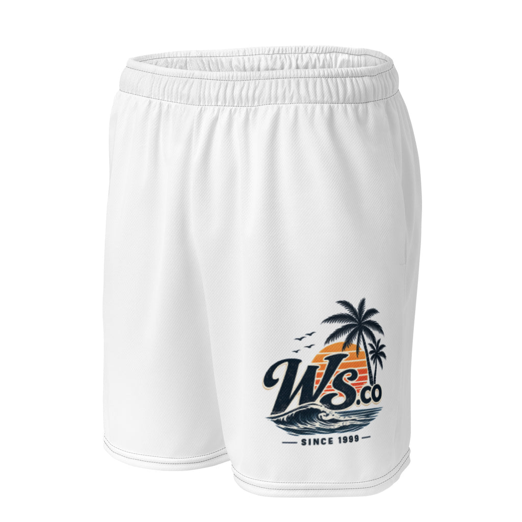 Woman modeling WaveSurfing™ white unisex mesh shorts at the beach beside a vintage camper van. Breathable athletic shorts designed for workouts, travel, beach adventures, and everyday comfort.